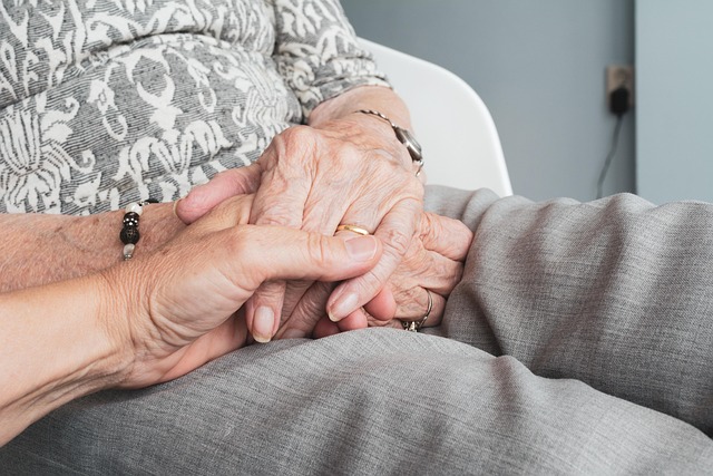 Close-up of a caregiver gently holding the hands of an older adult, symbolising compassion and the balance between duty of care vs individual rights.