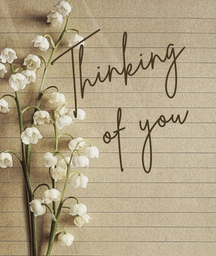 A delicate bouquet of white lily of the valley flowers placed on lined brown paper with the words “Thinking of you” written in cursive — a gentle, symbolic image for leaving a care placement.